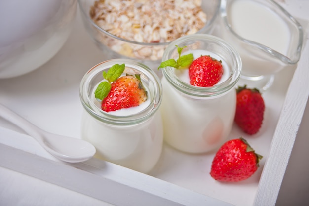 Yogur casero natural en un frasco de vidrio con fresas frescas y muesli cerca