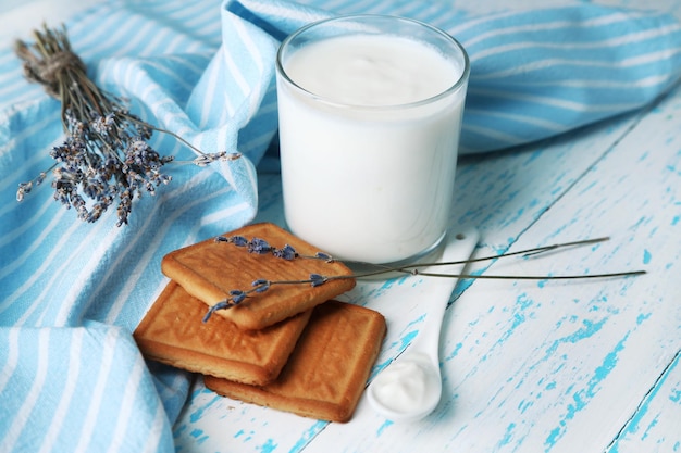 Yogur casero en vidrio y sabrosa galleta sobre fondo de mesa de madera