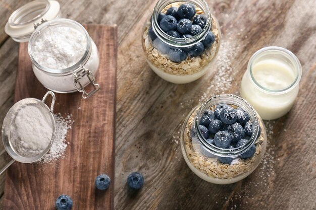 Yogur con copos de avena y arándanos en frascos de mesa de madera