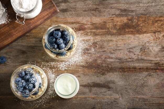 Yogur con copos de avena y arándanos en frascos de mesa de madera