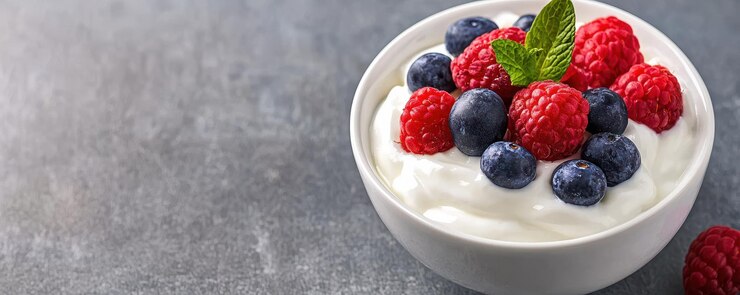 El yogur cremoso cubierto de arándanos y frambuesas frescas adornado con hojas de menta crea una opción de bocadillo vibrante y saludable este cuenco colorido es perfecto para un regalo refrescante