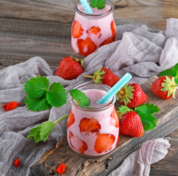 Yogur de fresa en un frasco de vidrio con una pajita de plástico