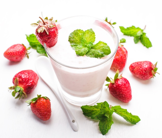 Yogur de fresa en vidrio sobre la mesa blanca