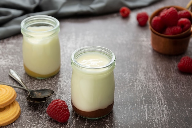 Yogur fresco en frasco de vidrio con frutas sobre fondo oscuro. Comida sana, diario de leche.