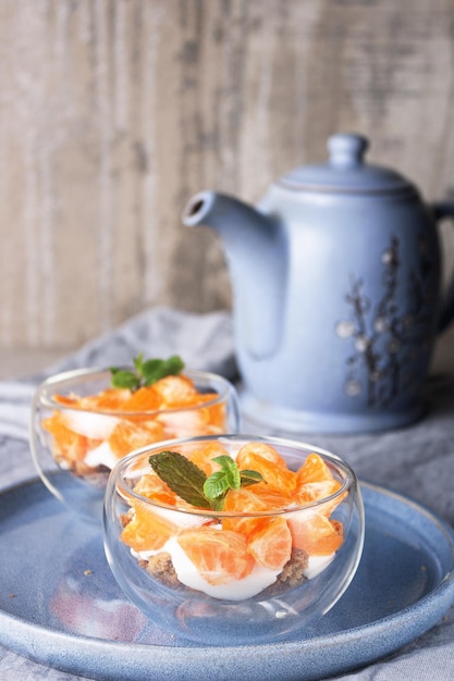 Yogur con galletas de avena y rodajas de mandarina en vasos de vidrio