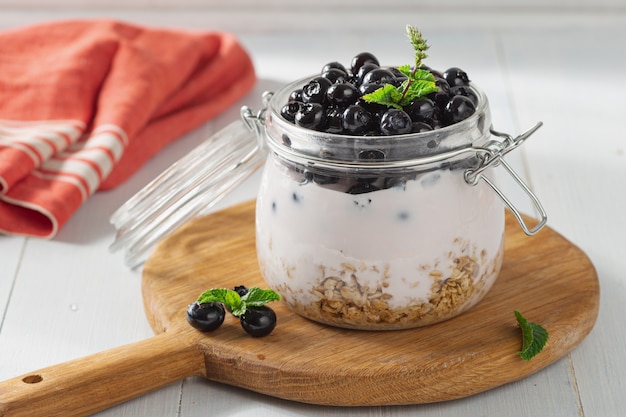 Yogur de granola en frasco de vidrio sobre una tabla de madera en la cocina de casa