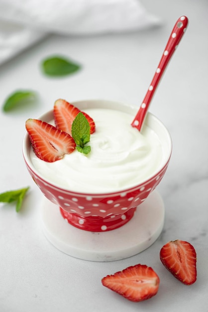 Yogur griego casero fresco con fresas en un tazón rojo