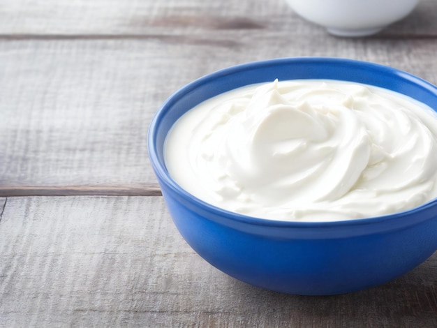 Yogur griego en cuenco azul en una mesa de madera rústica