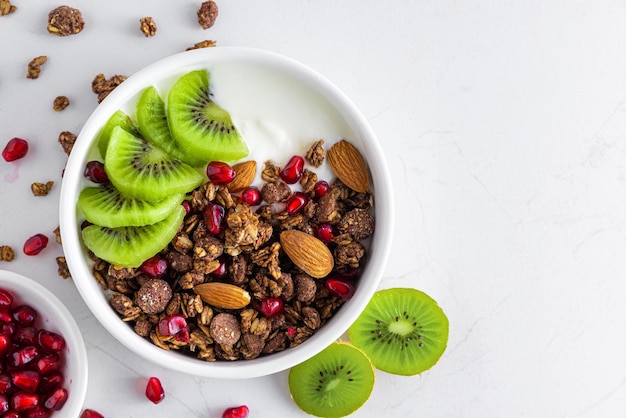 Yogur griego con granola de chocolate, kiwi, semillas de granada y almendras en un bol