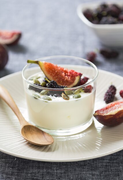 Yogur griego con higo, moras y pepitas de calabaza en un vaso