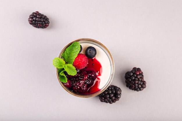 Yogur griego con mermelada de frutos rojos y menta en taza de cerámica foto de alta calidad