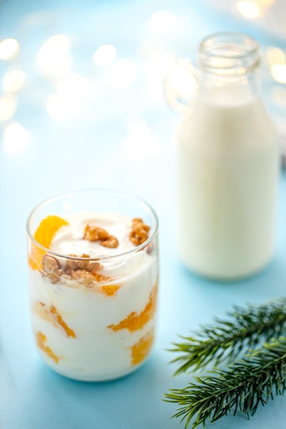 Yogur griego con naranja y nueces en vasos sobre una mesa azul alimentos saludables concepto de alimentación saludable