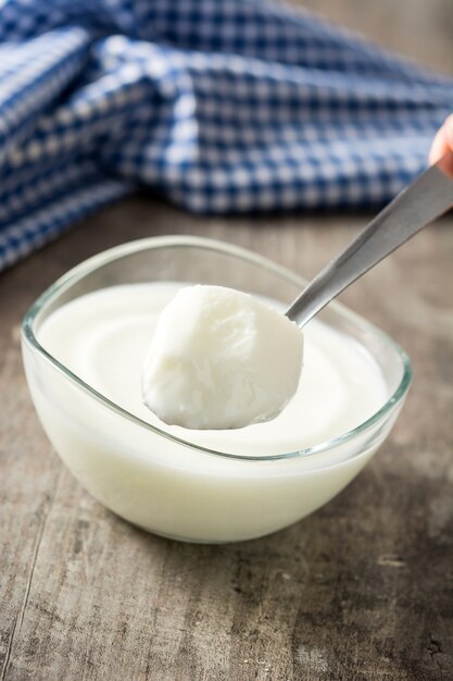 Yogur griego en recipiente de vidrio sobre mesa de madera