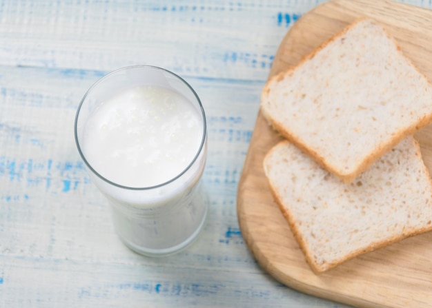 Yogur de kéfir en un vaso sobre un fondo de rebanadas de pan blanco sobre un fondo de madera