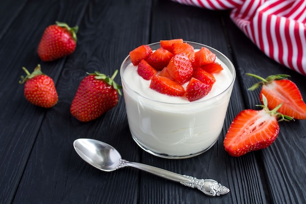 Yogur de leche con fresa en la madera negra