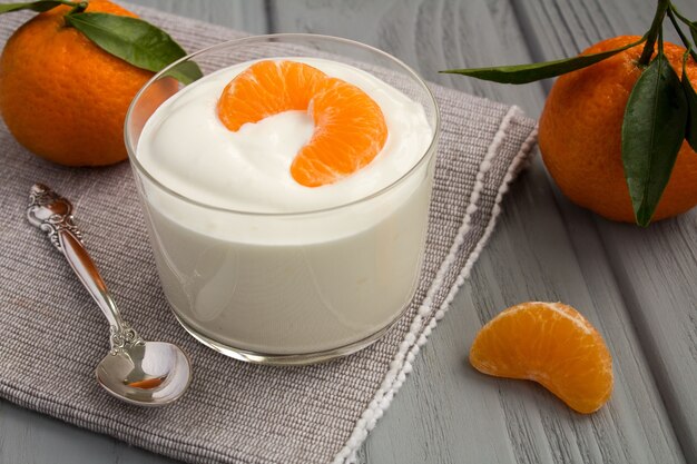 Yogur de leche con mandarina sobre fondo gris