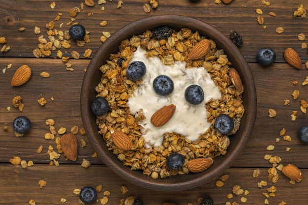 Yogur, muesli, nueces y arándanos en un recipiente sobre la mesa. Endecha plana.