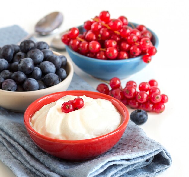 Yogur natural, bayas frescas y cereales en una mesa de madera oscura. Concepto de desayuno saludable