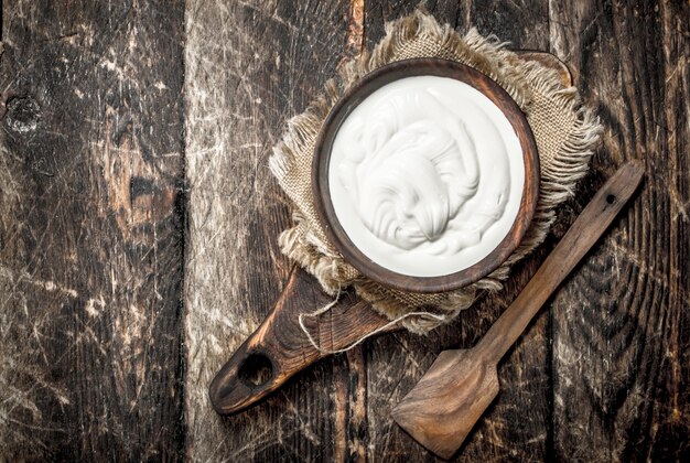 Yogur natural en un bol. Sobre un fondo de madera.