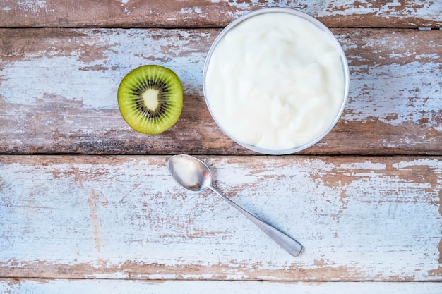 Yogur natural y kiwi en mesa de madera.