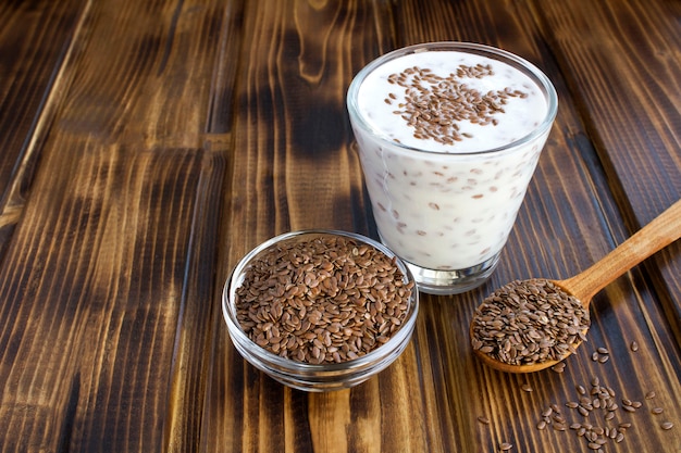 Yogur o kéfir con semillas de lino en el vaso sobre la superficie de madera marrón. Copia espacio