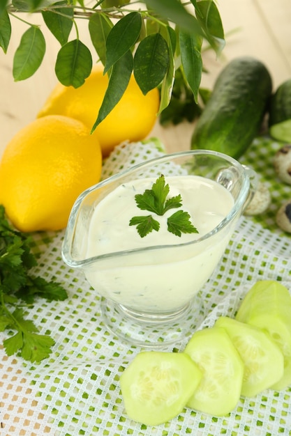 Yogur de pepino en recipiente de vidrio sobre servilleta de color sobre fondo de madera de color