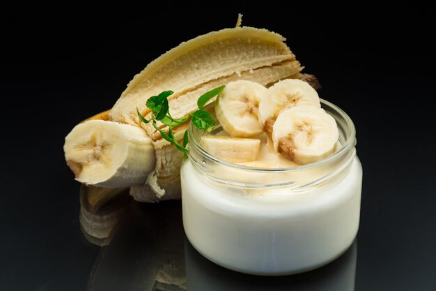 yogur de plátano dulce casero en un frasco de vidrio aislado sobre un fondo negro