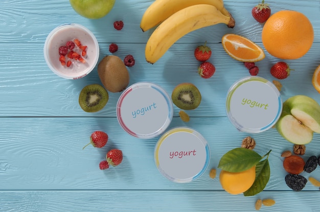 Yogur en un recipiente con frutas tropicales sobre un fondo de madera, vista superior. concepto de alimentación saludable