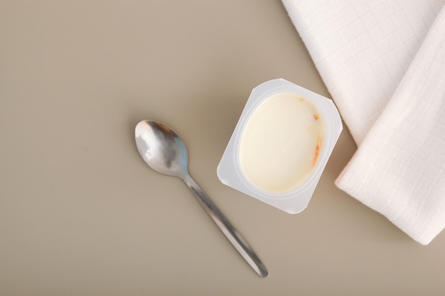 Yogur sabroso en un vaso de plástico sobre un lugar de mesa de color para insertar texto