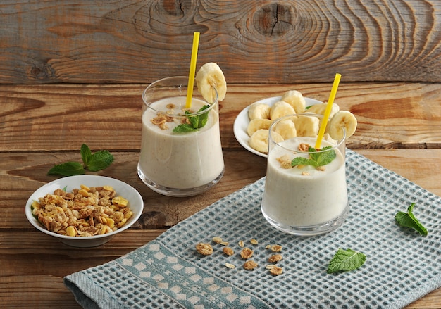 Yogur en tazas con una pajita con muesli y plátano