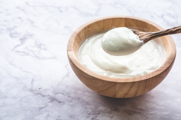 Yogur en un tazón de madera sobre mesa de mármol