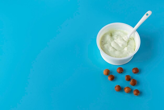 Yogur en un vaso sobre un fondo azul con nueces Un saludable desayuno de dieta ligera Productos lácteos