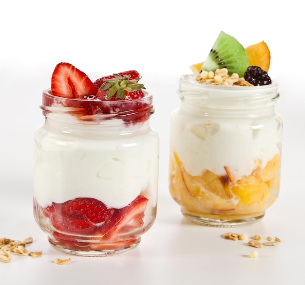 Yogures con kiwis y bayas en frascos en la mesa