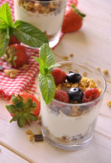 Foto yogurt con arándanos, fresas, muesli y menta.