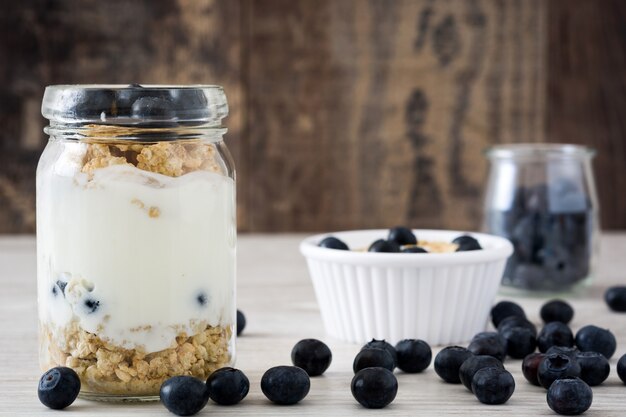 Yogurt con arándanos en mesa de madera blanca