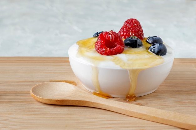 Yogurt con frambuesa y arándanos en una tabla de madera