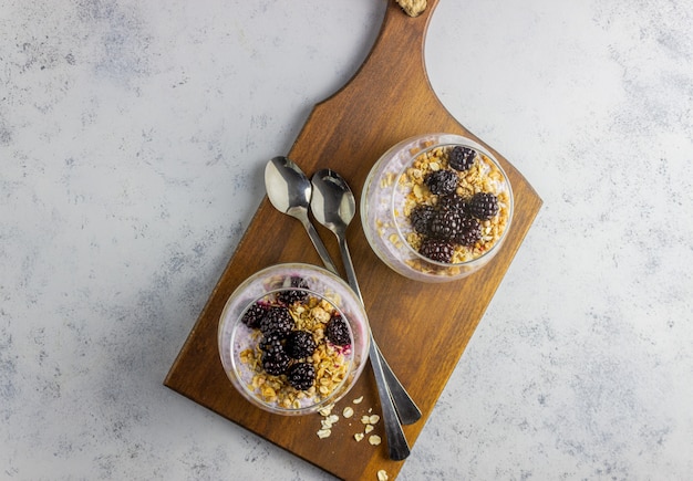 Yogurt con granola, semillas de chia y moras sobre un fondo gris. desayuno. alimentación saludable.