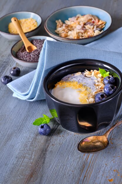 Yogurt con muesli y arándanos con menta, postre saludable en madera