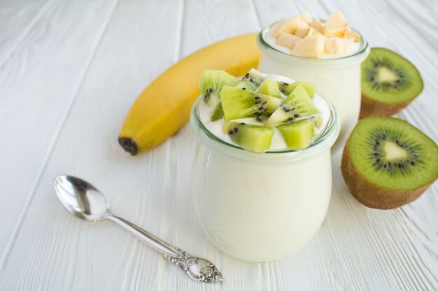 Yogurt natural de leche con kiwi y plátano en frascos de vidrio