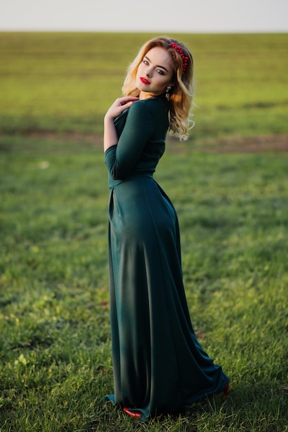 Foto yong menina loira elegante com vestido verde no jardim na primavera.