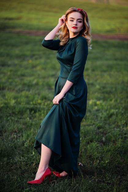 Yong menina loira elegante com vestido verde no jardim na primavera.