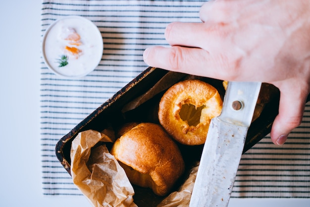 Yorkshire-Puddings mit den Fischen, die, in einem alten Metallbehälter, Hände im Rahmen, Draufsicht füllen