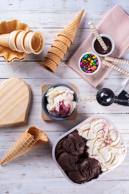 Foto yougurt helado con frutos rojos y helado de chocolate juntos en una caja de entrega. composición con conos.