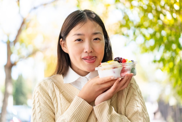 Youing mujer china sosteniendo un plato de fruta al aire libre