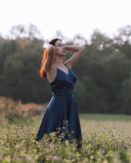 Foto youmg mujer en vestido azul de pie en el campo