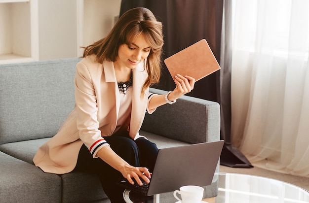 Youn mulher adulta trabalhando no laptop enquanto está sentado no sofá