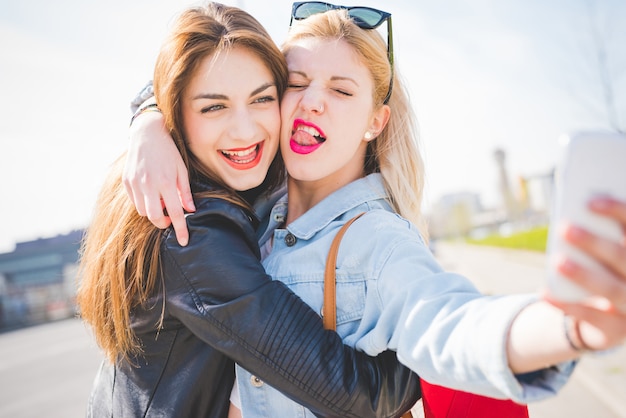 Youn schönes blondes und Brunettemädchen, das selfie nimmt