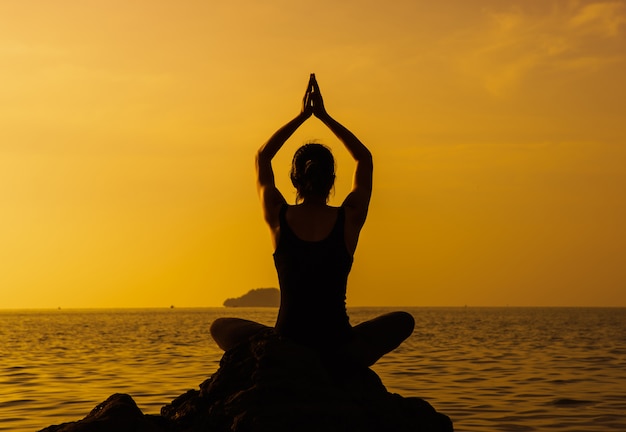 Foto young cabe mulher usando a técnica de yoga para meditação e bem-estar na praia ao nascer do sol