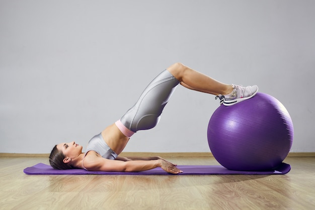 Young fit mujer haciendo ejercicio en un gimnasio. Chica deportiva está entrenando cross fitness con Pilates Balls.