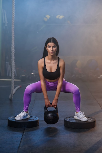 Young fit mujer haciendo ejercicio con pesas en el gimnasio.